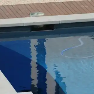 Tuyau d'aspirateur manuel plongé dans une piscine