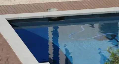 Tuyau d'aspirateur manuel plongé dans une piscine