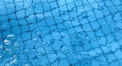 Surface d'eau de piscine avec reflets bleus et bulles